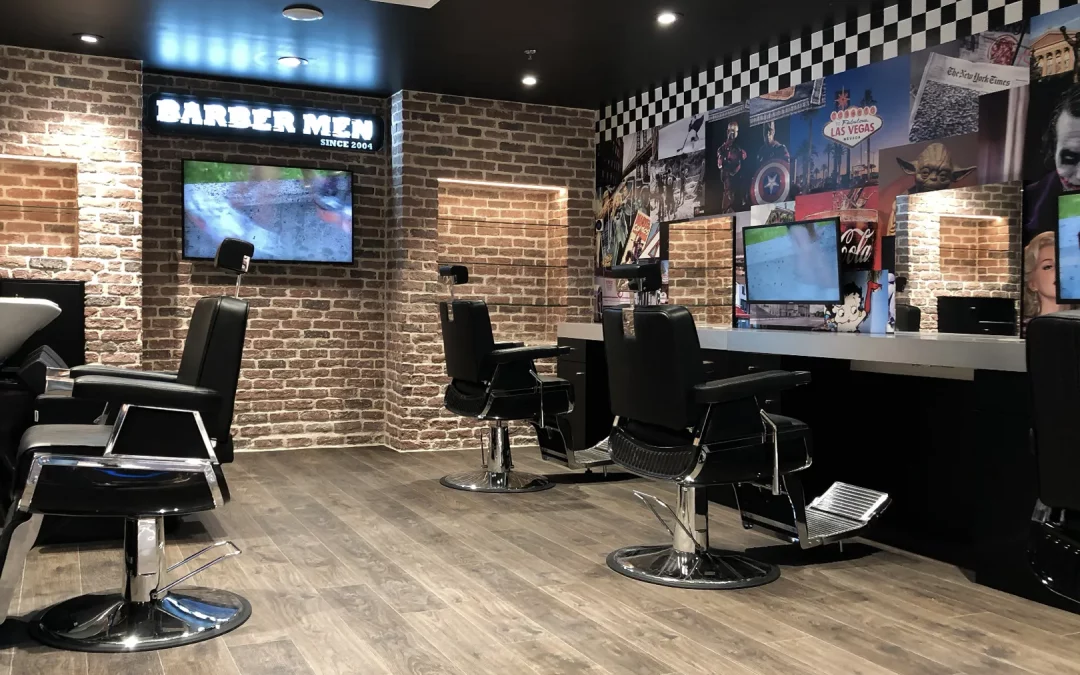 Intérieur du salon BARBER MEN à Istres : postes de coiffage, enseigne néon, vitrine et TV.