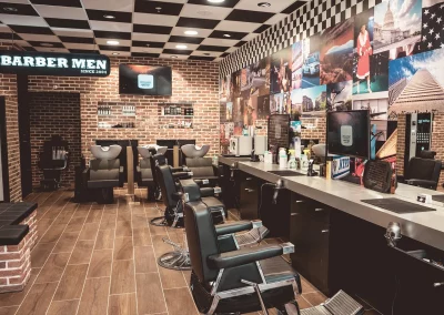 Intérieur du salon BARBER MEN à Lille : postes de coiffage, enseigne néon, bacs à shampooing et vitrine de produits.