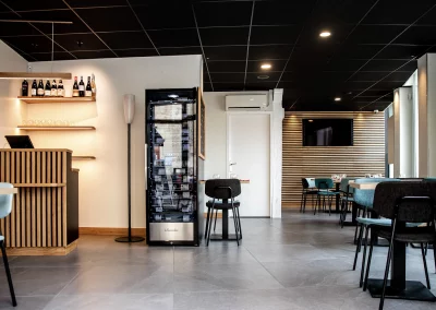 Vue de l’espace restaurant de L’Acte 08, mettant en avant un meuble réfrigéré dédié aux vins, un aménagement élégant et un mobilier moderne.