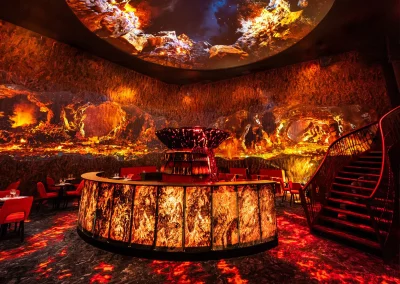 Salle immersive du restaurant Magmatic avec bar central et projections volcaniques spectaculaires