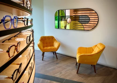 Miroir mural design et fauteuils d’attente jaunes dans un opticien.