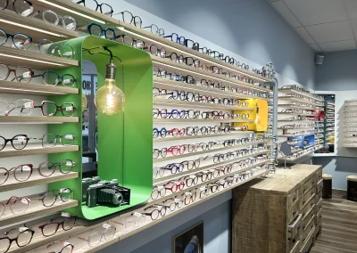 Présentation murale des montures dans la boutique Le Marchand de Lunettes à Veigné