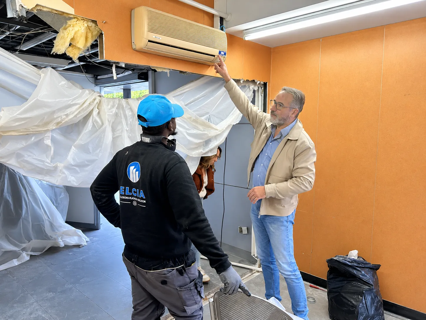 Visite de chantier dans le kiosque RÉMI de Tours : un représentant d'Ergonium échange avec un intervenant devant une cloison partiellement déposée.